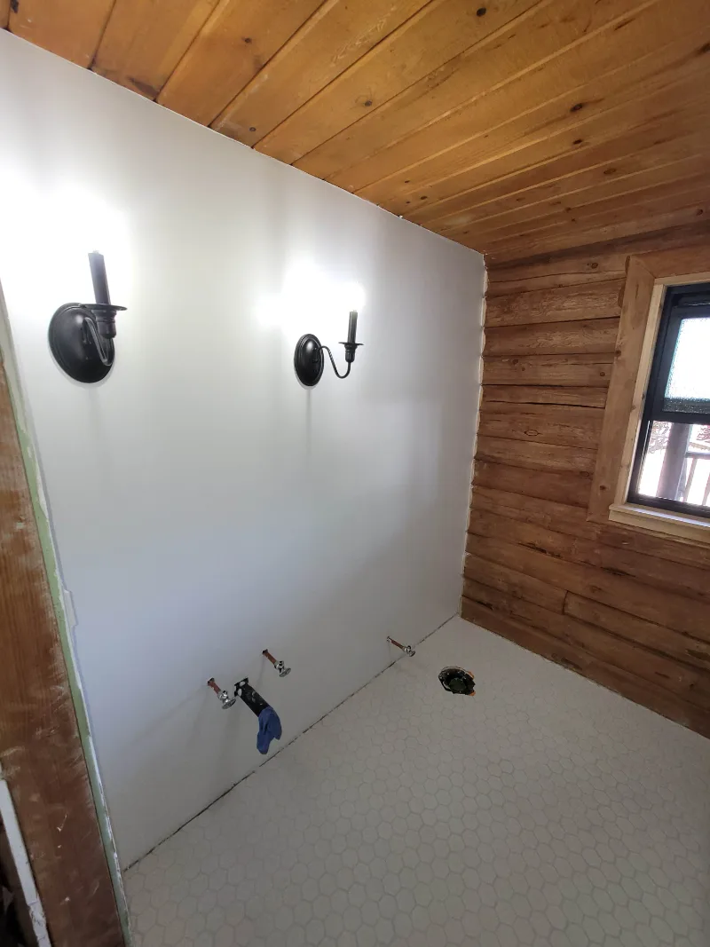 Bathroom during the remodel: floor tiled, walls finished, plumbing stubbed out
