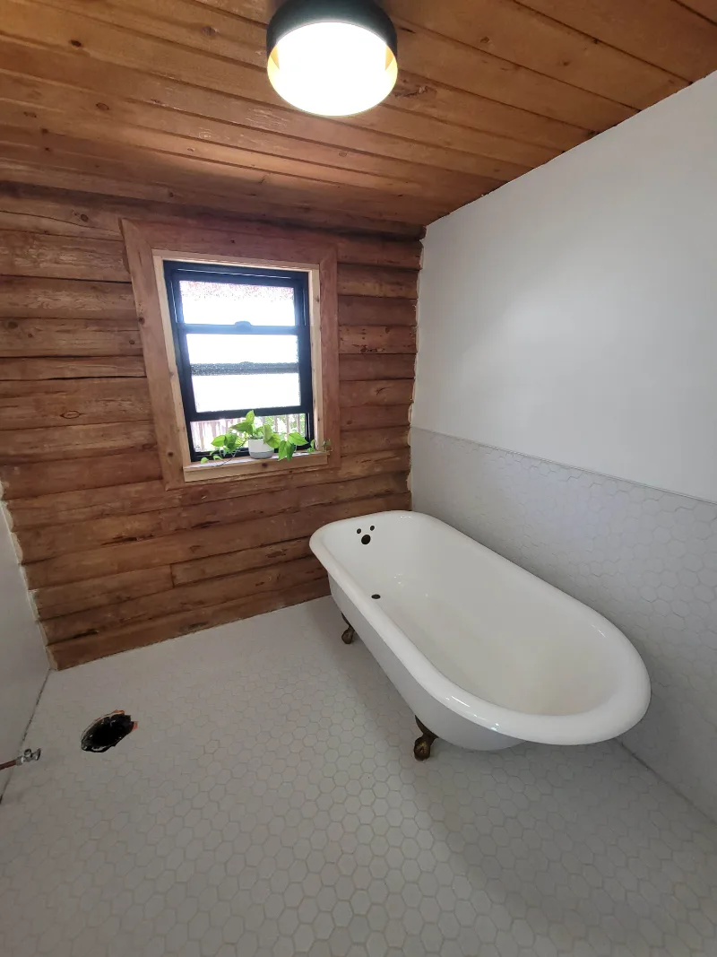 Finished bathroom with clawfoot tub under the window
