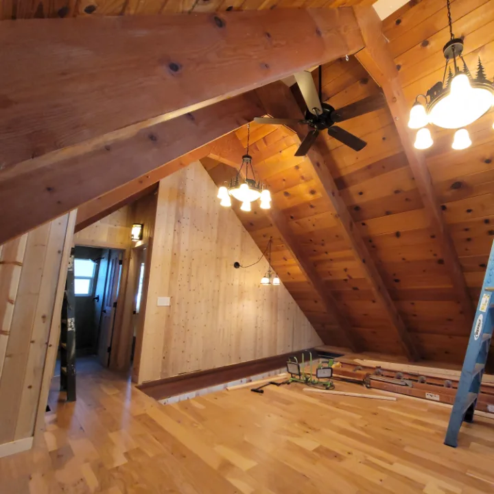 Vaulted upstairs room with new wood flooring and paneling, ladder still up