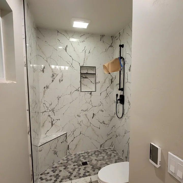 Walk-in shower with marble-look wall tile, built-in niche and bench