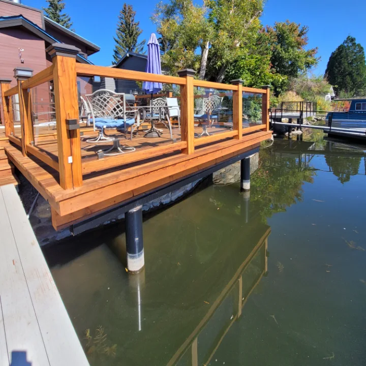 Finished wood deck with glass railing, built on piers
