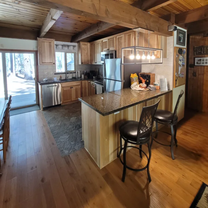 Finished kitchen with hickory cabinets, granite counters and an island under timber beams