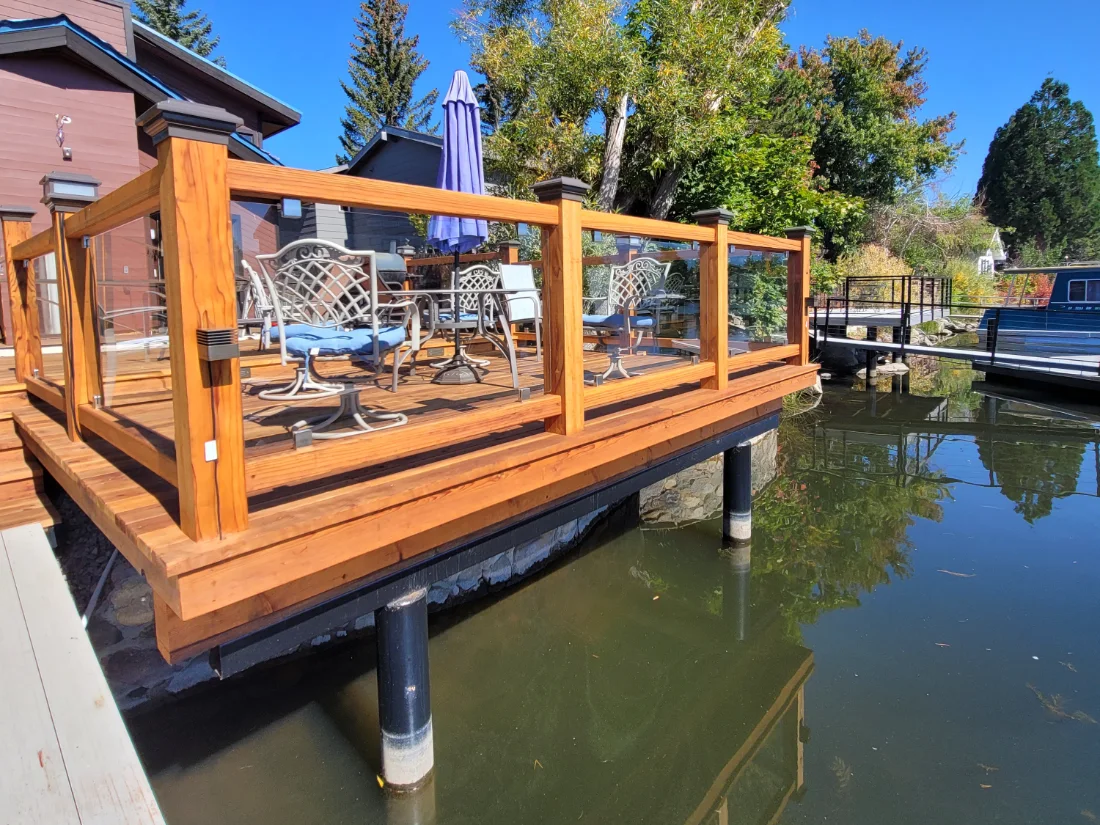 Finished wood deck with glass railing, built on piers