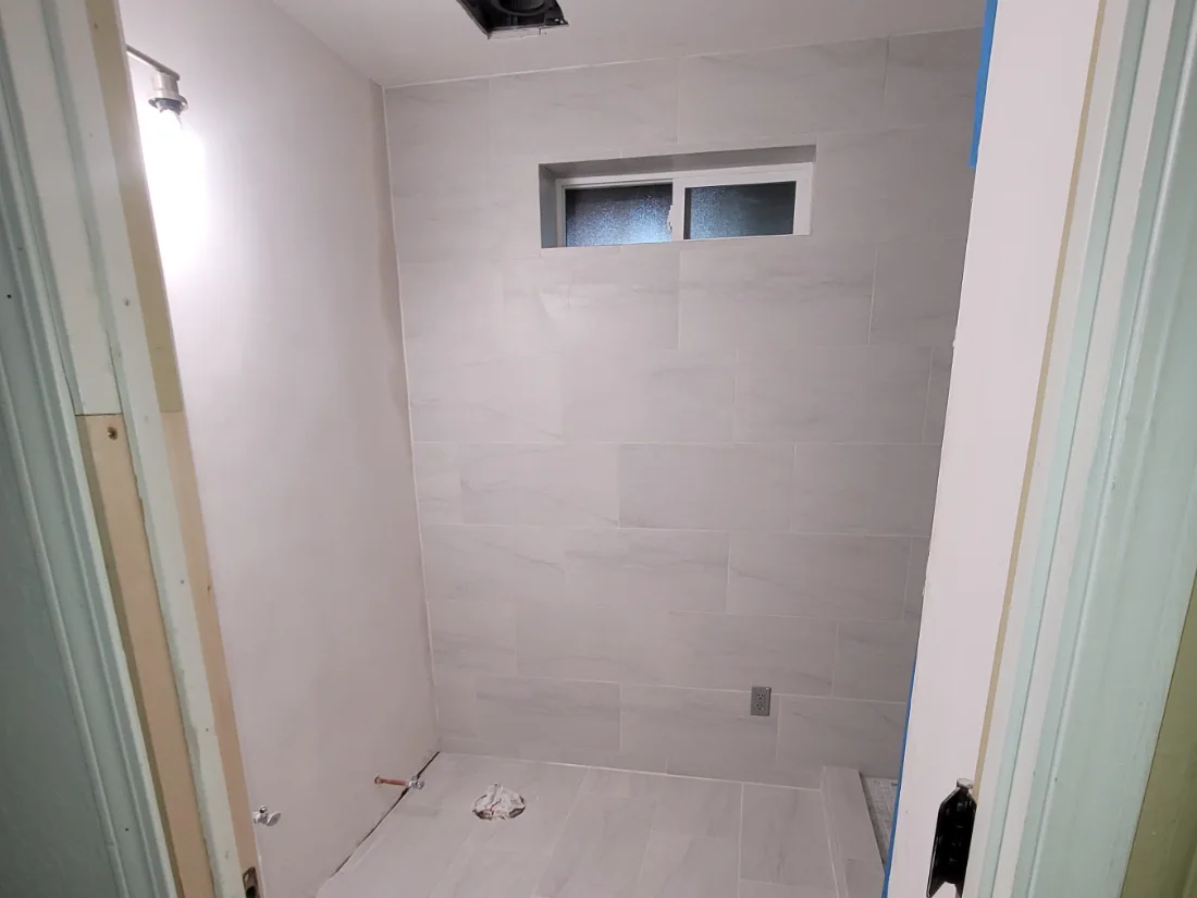 Bathroom being put back together: new wall and floor tile set, fixtures still to come