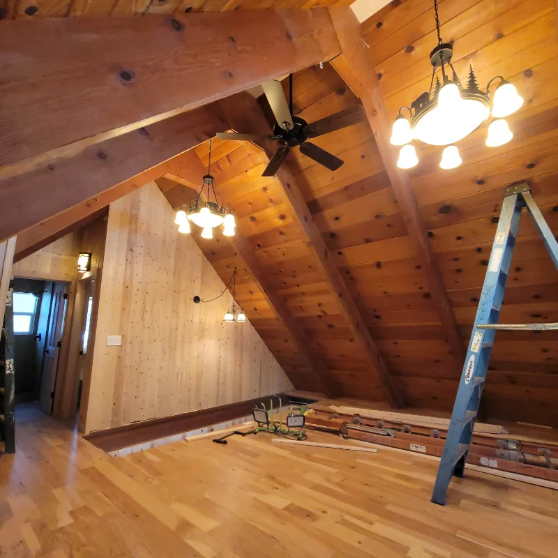Vaulted upstairs room mid-renovation with new wood ceiling and flooring