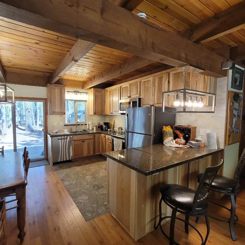 Finished kitchen with timber beams, hickory cabinets and a stone-topped island