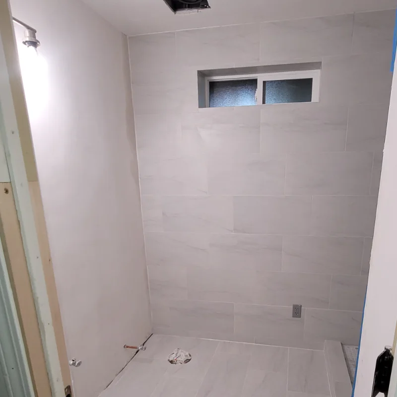 Bathroom being put back together: new wall and floor tile set, fixtures still to come