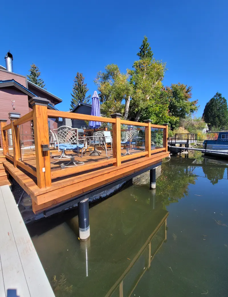 Finished wood deck with glass railing, built on piers