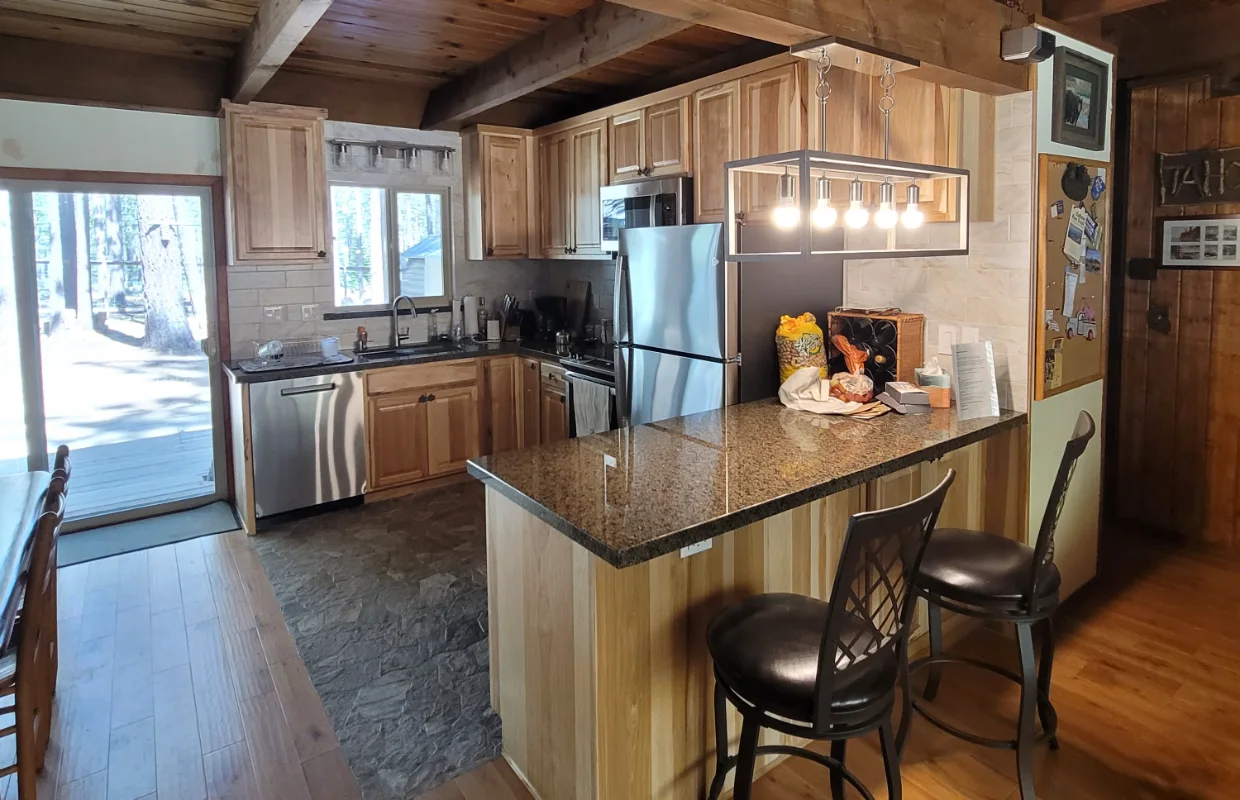 Finished kitchen with hickory cabinets, granite counters and an island under timber beams